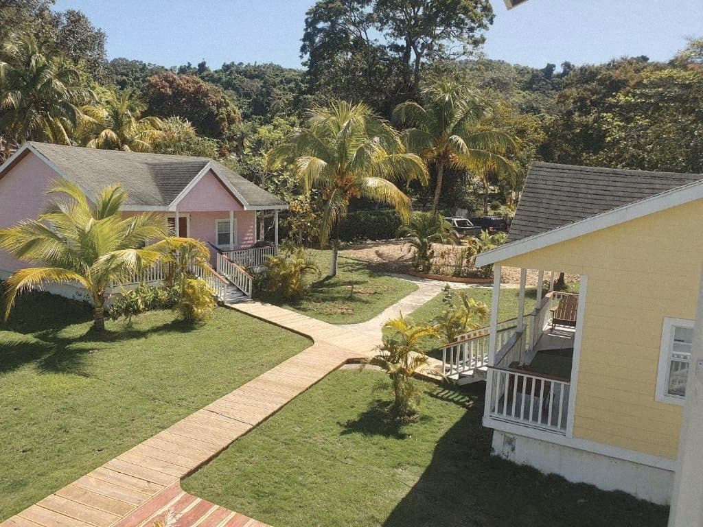 Pink and yellow cottages along a wooden path through the lawn